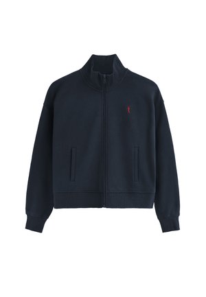 Chaqueta de cremallera azul marino hecha de felpa, con un alto cuello, dos bolsillos frontales, puños acanalados y un logo rojo en el pecho.