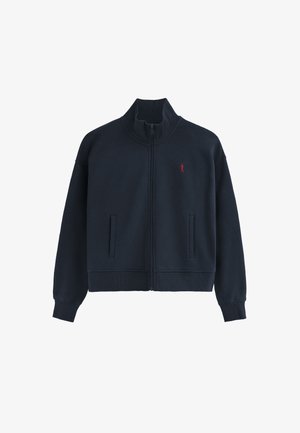 Marineblauwe batterijjack van fleece, met een hoge kraag, twee voortassen, geribbelde manchetten en een rood logo op de borst.