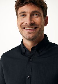 Zwarte overhemd met knopen en een kraag, gemaakt van een textuurstof en met een sluiting aan de voorkant met knopen. Het overhemd heeft korte mouwen en geen zichtbare patronen.