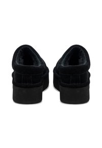Črne nubuk slip-on čevlje z debelim platformnim podplatom, okroglim nosom in mehkim krznom znotraj. Petni del ima gladko, mat površino.