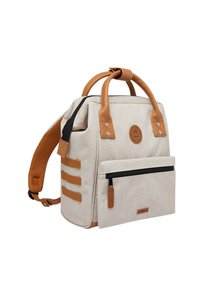 Beige fabric backpack with tan leather accents, double handles, side straps, and a front zippered pocket. Compact rectangular design.