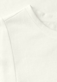 Hvid bomulds t-shirt stof med en glat overflade. Synlig rund hals og korte ærmer, der demonstrerer et simpelt design og rene sømme.