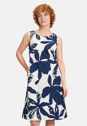 Sleeveless dress in cream with large navy floral pattern. A-line cut, round neckline, and a smooth cotton fabric with slight sheen.