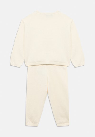 Σετ μαλακιάς βαμβακερής φόρμας σε κρεμ χρώμα. Το φούτερ έχει ριμπ μανσέτες και τελείωμα, ενώ το παντελόνι διαθέτει ελαστική μέση.