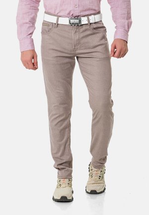 Beige gestreifte Hosen aus einer Baumwollmischung, mit einem Slim-Fit-Design, einem weißen Gürtel und kombiniert mit hellen Sportschuhen.