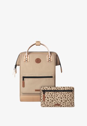 Sac à dos en tissu beige avec des accents marron, poignée supérieure, poche zippée à l'avant et une trousse assortie imprimée léopard avec une fermeture zippée noire et une étiquette logo marron.