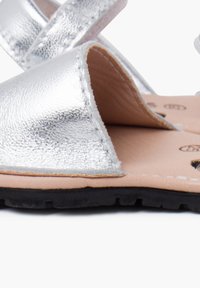 Silberne metallische Sandalen mit einer weichen Lederinnensohle, offener Zehenpartie, minimaler Naht und einer strukturierten Oberseite mit verstellbaren Riemen.