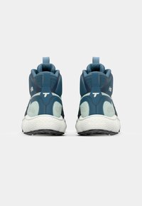 Baskets de sport bleues et teal avec une surface texturée, un design arrondi, un col rembourré et une semelle blanche avec un motif de semelle.
