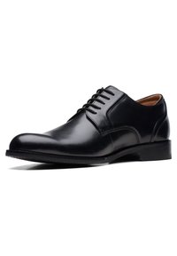 Scarpa da uomo in pelle nera, con punta arrotondata, design con lacci, finitura liscia e tacco basso impilato. Presenta accenti di cucitura minimali.