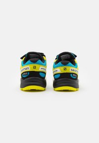 Black and yellow athletic shoes with a mesh upper, featuring blue accents, padded collar, and contrasting sole for traction and support.