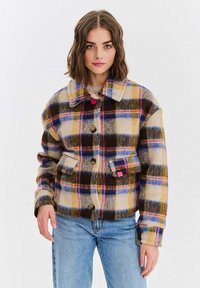 Pločkovaná bunda v béžové, hnědé a žluté barvě, se velkými knoflíky, límcem a předními kapsami. Měkká textura s barevným kostkovaným vzorem.