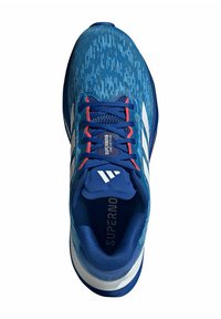 Chaussure de sport bleue avec une tige texturée, des accents rouges et des rayures blanches. Elle est dotée d'un col rembourré et d'un logo imprimé sur la languette.