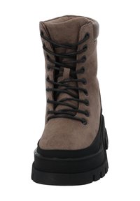 Bruine suède laars met zwarte rubberen zool, ronde neus, metalen veteroogjes en veters. Gestructureerd bovenwerk met gevoerde kraag voor comfort.