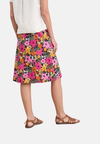 Floral A-line skirt featuring a navy background with bright pink, orange, and yellow flowers. Paired with brown strappy sandals.