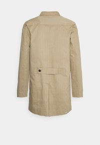 Beige long-sleeve coat with a collar, featuring horizontal stripes, a rear belt with a button detail, and a subtle texture.