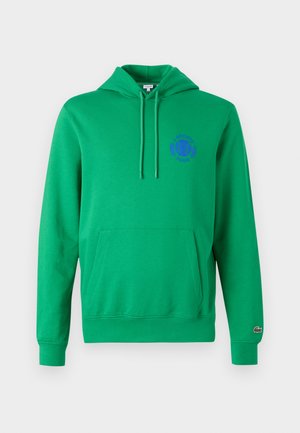 Roheline kapuutsiga pusa, millel on kenguru tasku, nööridega kapuuts ja lilla tikandiga logo rinnal. Ribidega varrukaotsad ja alumine äär. Pehme tekstuur.