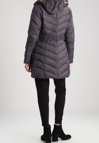 Gray puffer coat with chevron pattern, belted waist, and hood. Worn over black pants and ankle boots. Smooth texture, lightweight design.