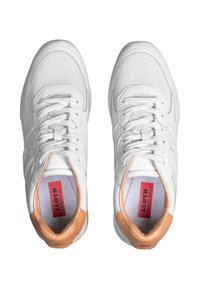 Baskets blanches en cuir avec une texture en maille, bout rond et accents bruns contrastants au niveau du talon. Design àlacets avec une marque rouge à l'intérieur.
