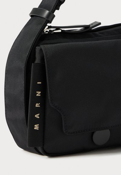 Geantă crossbody neagră cu curea ajustabilă, buzunar frontal cu clapetă, detaliu cu fermoar și etichetă din material cu lettering "MARNI" pe lateral.