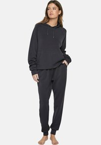 Donkergrijze hoodie met een relaxte pasvorm, buidelzak en trekkoord. Gekoeld met bijpassende joggingsbroek met elastische boorden en tailleband.