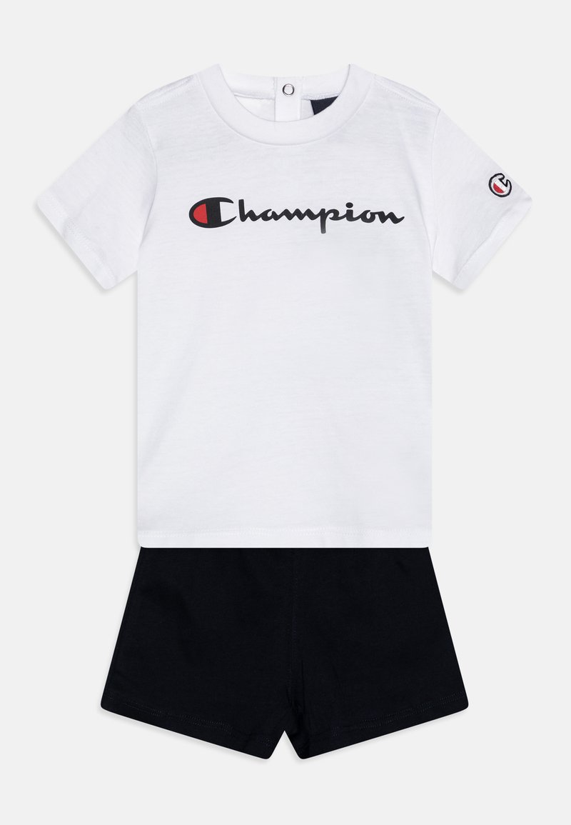 Weißes Baumwoll-T-Shirt mit schwarzem "Champion"-Logo, kombiniert mit schwarzen Shorts. Das T-Shirt hat kurze Ärmel und einen Snapback-Verschluss.
