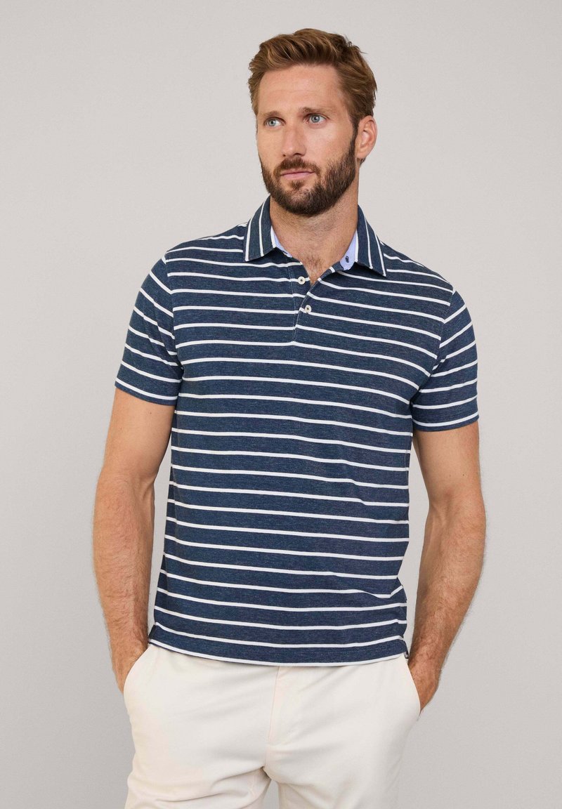 Granatowa koszulka polo w białe poziome paski, z krótkimi rękawami i kołnierzykiem. Posiada dwa guziki oraz kontrastowy detal wewnętrznego kołnierza.