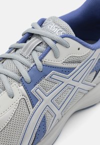 Light gray mesh running shoe with blue accents, featuring a textured surface, lace-up design, reinforced toe, and iconic logo on the tongue.