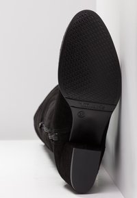 Stivale alla caviglia in suede nero con suola in gomma testurizzata, dotato di zip laterale e dettagli cuciti. Taglia 37 riportata sulla suola.