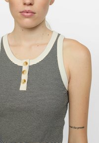 Top de tirantes a rayas en blanco y negro con un cuello acanalado en crema y cuatro botones dorados en la tapeta, con un diseño ajustado.