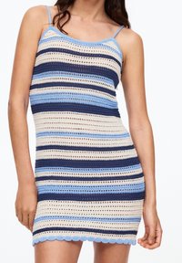 Robe en crochet avec des rayures horizontales bleu marine, bleu clair et beige, munie de fines bretelles et d'un ourlet festonné.