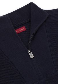 Granatowy sweter z dzianiny z kołnierzem stójkowym i zamkiem błyskawicznym na pół. Posiada subtelny wzór teksturowy oraz uchwyt zamka błyskawicznego w stylu breloka.