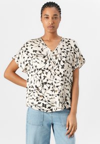Kortermet bluse med V-hals laget av lett stoff, med et blomsterdesign i svart og beige med brune aksenter. Løs passform.