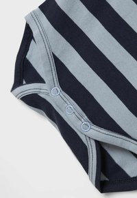 Randig babydress i marinblått och ljusblått. Mjukt bomullsmaterial med tryckknappar och kontrasterande sömdirkt längs kanterna.
