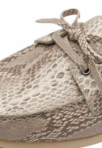Chaussure à lacets avec une tige en cuir à imprimé serpent beige et marron clair, conception à bout rond et surface texturée.