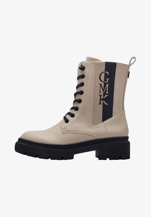 Botine din piele artificială bej, cu accente negre, șireturi frontale, talpă chunky și panou lateral cu marcă. Material texturat.
