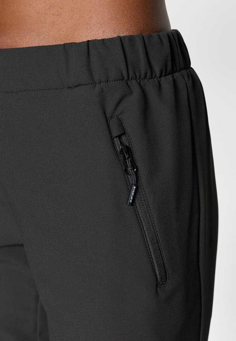 Pantalons de sport noirs en tissu texturé, avec une taille élastique et une poche zippée sur le côté pour un rangement sécurisé.