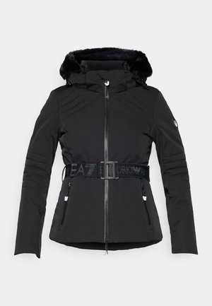 Črna zimska jakna s kapuco podloženo z umetnim krznom, spredaj z zadrgo, diagonalno prešita, z nastavljivim pasom in dvema stranskima žepoma z zadrgo.