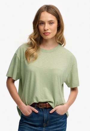 Lys grøn kortærmet t-shirt med rund halsudskæring, afslappet pasform og diskret tekstur. Sammen med mørkeblå jeans og et brunt vævet bælte.