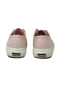 Un paio di sneaker basse in canvas rosa di Superga, viste da dietro, con suole in gomma bianca e logo del marchio sul tallone.