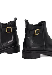 Black leather ankle boots with a textured finish, featuring a side buckle accent, elastic panels, and a sturdy rubber sole.