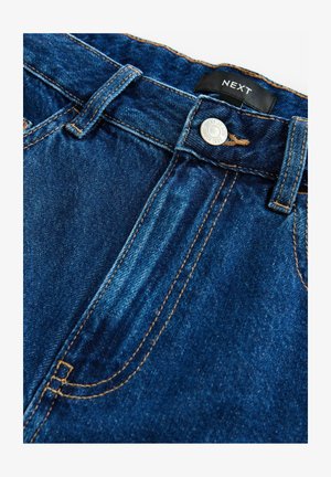 Tummansininen farkkuhousu, jossa on sileä pinta. Edessä on vetoketju ja nappikiinnitys, sekä oranssit tikkaus yksityiskohdat. Tunnuslukuna on "NEXT."