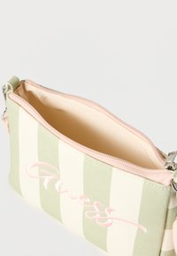 Μικρό ριγωτό πράσινο και λευκό τσαντάκι με φερμουάρ, με αχνό ροζ κέντημα "Guess" και μπεζ εσωτερική επένδυση.