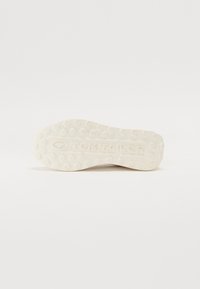 Tejfehér gumis sneaker talp, hatszögletű mintázattal és dombornyomott "TOM TAILOR" logóval. Lapos, textúrált a tapadás és tartósság érdekében.