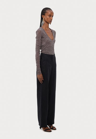 Top de manga larga con escote en V profundo en tela gris mélange, combinado con pantalones negros de pierna ancha de cintura alta y sandalias negras con tiras.