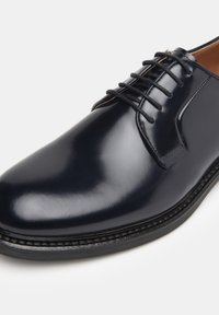 Navy leather dress shoe with a smooth, glossy finish, rounded toe, and detailed stitching on the sole. Features classic lace-up design.