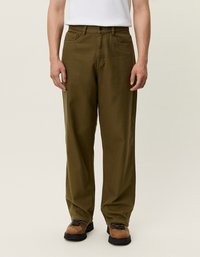 Ελαιοπράσινο βαμβακερό παντελόνι με ίσια γραμμή, διαθέτει δύο μπροστινές τσέπες και κλείσιμο με κουμπί. Φορεμένο με καφέ μποτάκια πεζοπορίας.