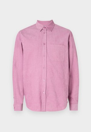 Ružová kordová košeľa s obojkom na gombíky, dlhými rukávmi a jednou náprsníkou. Má vertikálne žlabenie a zapínanie na gombíky vpredu.