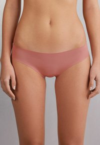 Roze naadloze hipster slipjes, gemaakt van zachte stof met een gladde textuur en zonder zichtbare stiksels. De tailleband zit vlak tegen de huid.