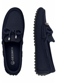 Marineblaue Stoffslippers mit strukturiertem Finish, ausgestattet mit dekorativen Schnürsenkeln und einer Gummisohle mit Profilpunkten.