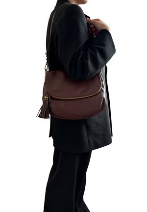 Borsa a spalla in pelle marrone con finitura liscia, chiusura con zip e un accento a nappina. Presenta una forma rotonda e una tracolla regolabile.